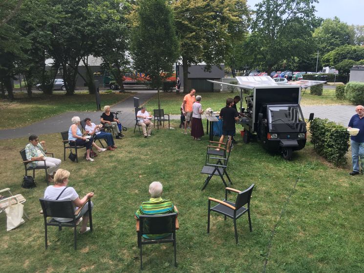 Kaffeemobil mit Menschen auf Stühlen, die im Kreis sitzen
