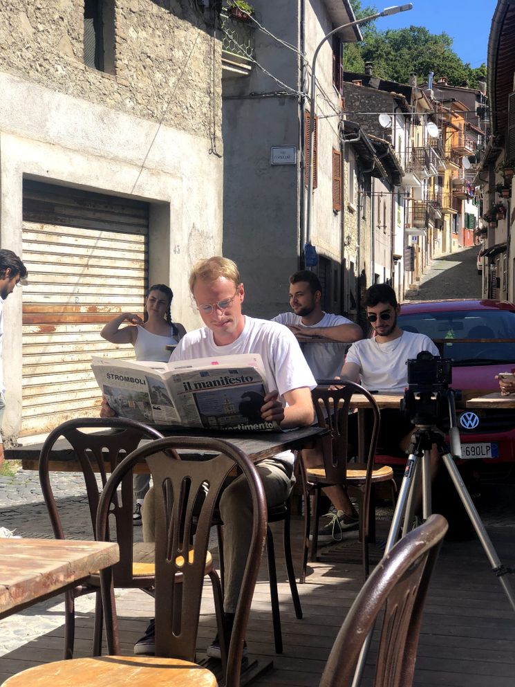 Niklas liest Zeitung vor einem Café