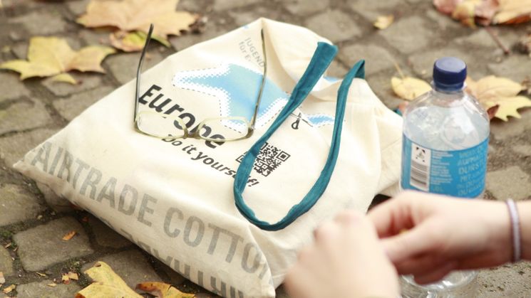 Tasche mit Aufdruck "Europe. Do it youself" liegt auf gefallenem Herbstlaub