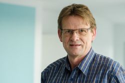 Prof. Dr. Rudolf Stark in kariertem Hemd vor neutralem Hintergrund